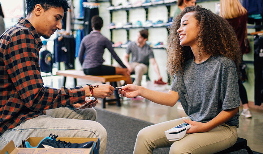Smiling woman accepting a customer’s card payment with a Clover Flex in a shoe shop
