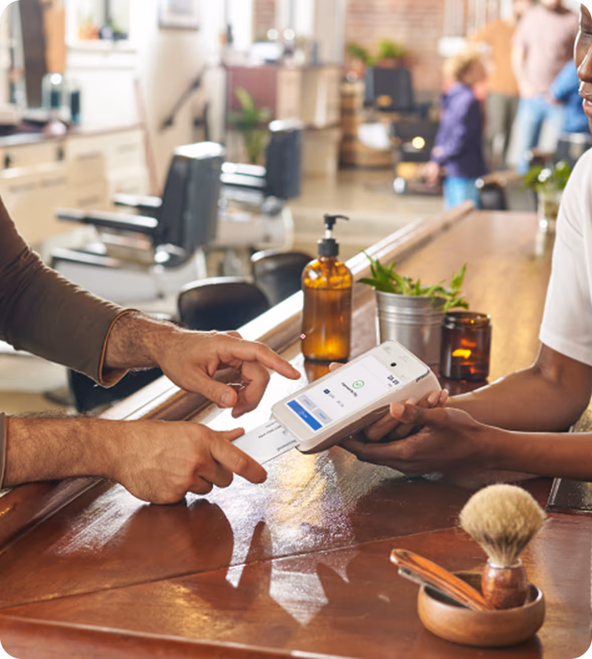 Customer paying at a salon counter with a handheld payment terminal